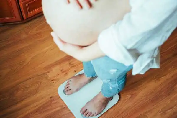 Image of woman weighing herself and experiencing weight gain through pregnancy Portland Bill